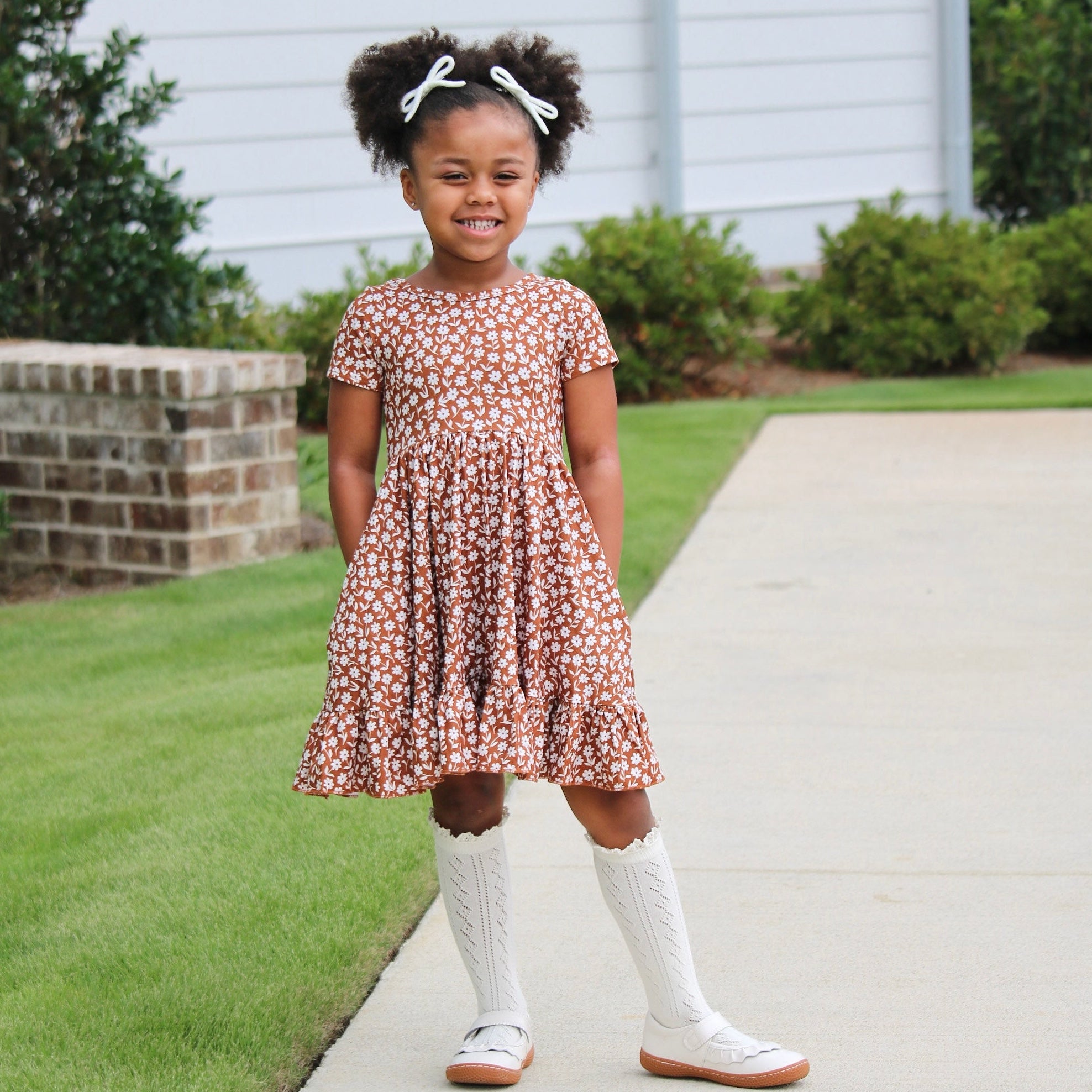 little girl standing outside wearing sugar almond floral fall dress with matching ivory lace top knee high socks