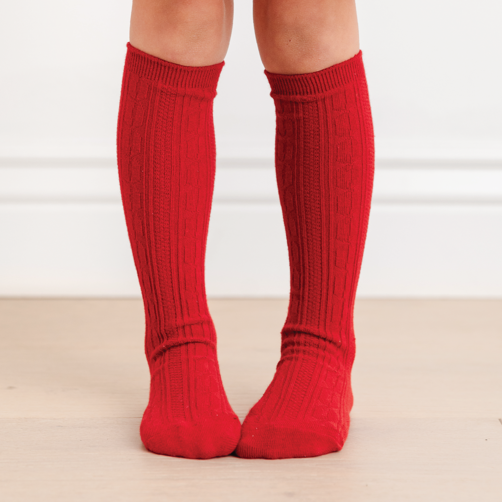 little girl legs wearing cherry red cable knit knee high socks