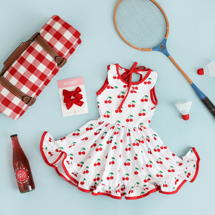 styled outfit image of girls cherry print summer tank top style dress with matching red linen pigtail hair bows