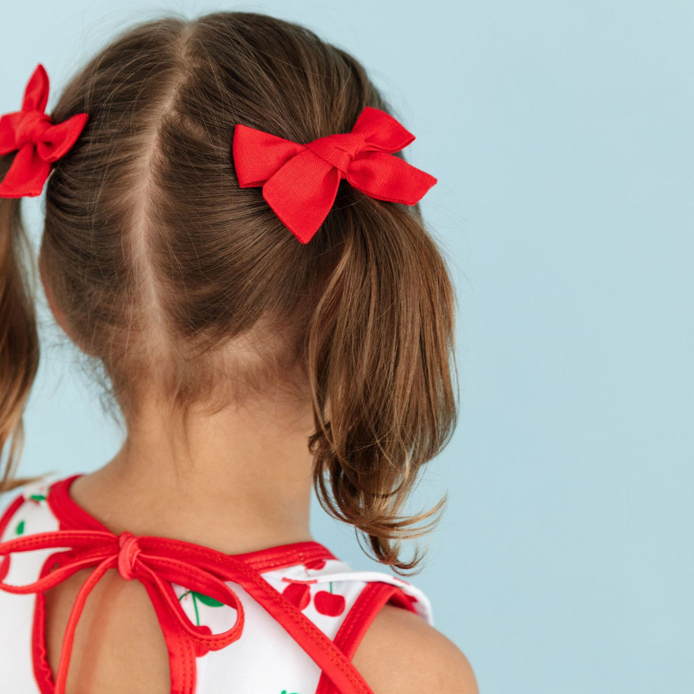 little girl in cherry dress with matching red linen pigtail bows