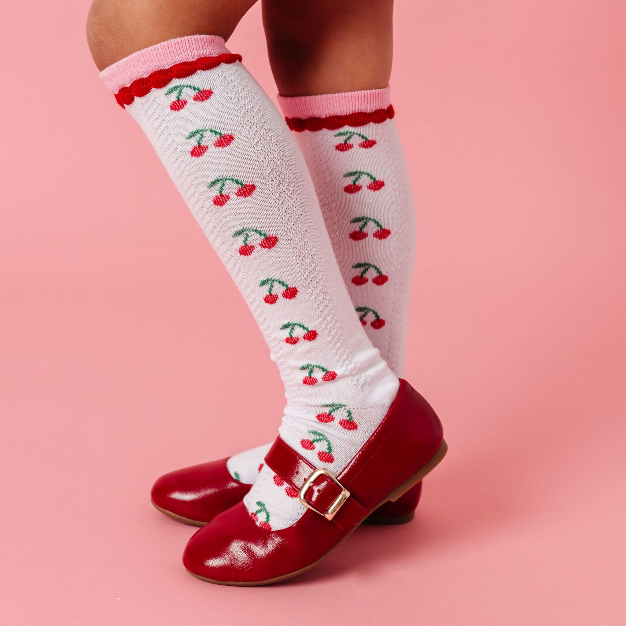 girl in red mary janes with cherry print knee high socks paired bright red velvet skort