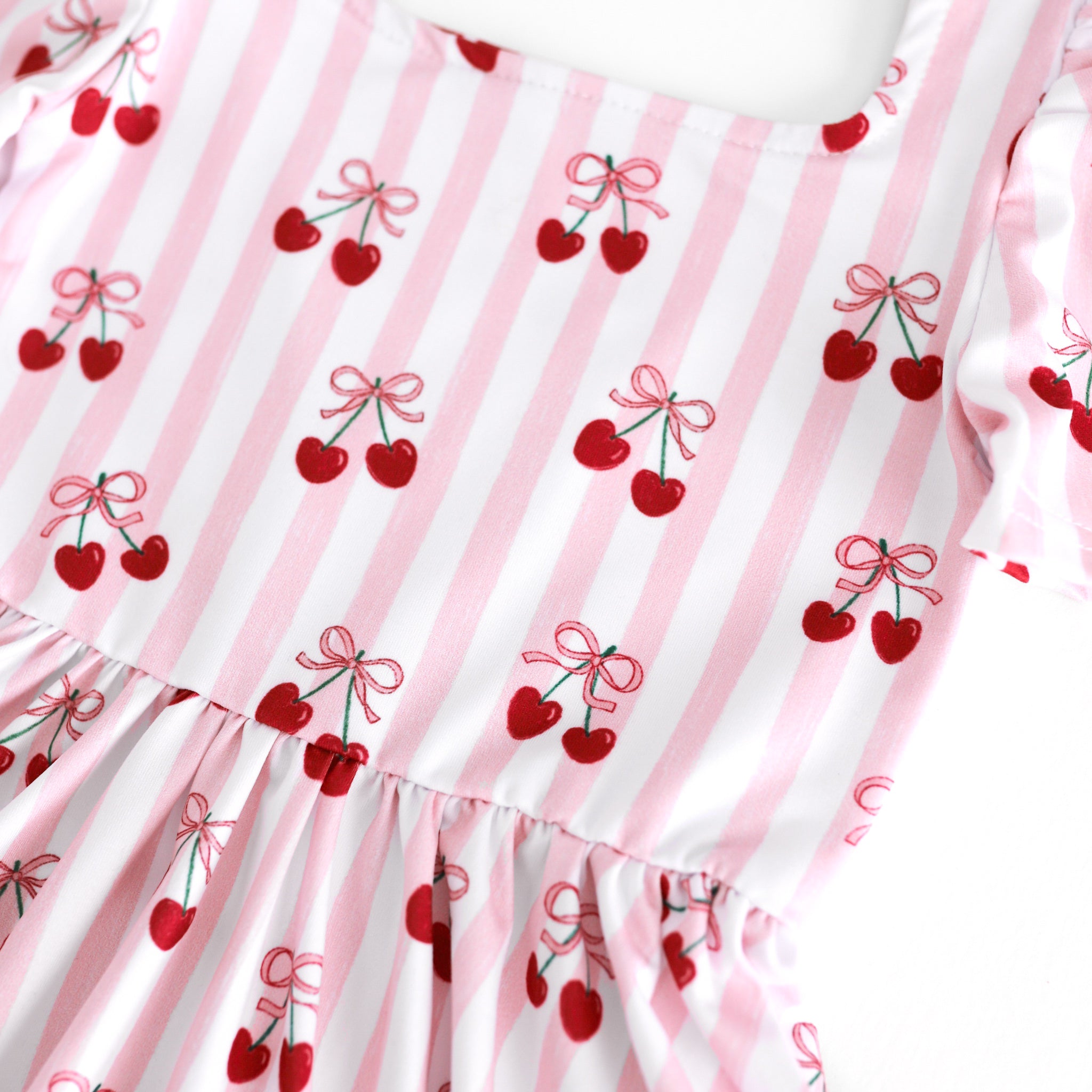 closeup of white and pink striped print twirl dress bodice with ribbon tied cherries