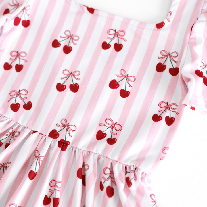 closeup of white and pink striped print twirl dress bodice with ribbon tied cherries