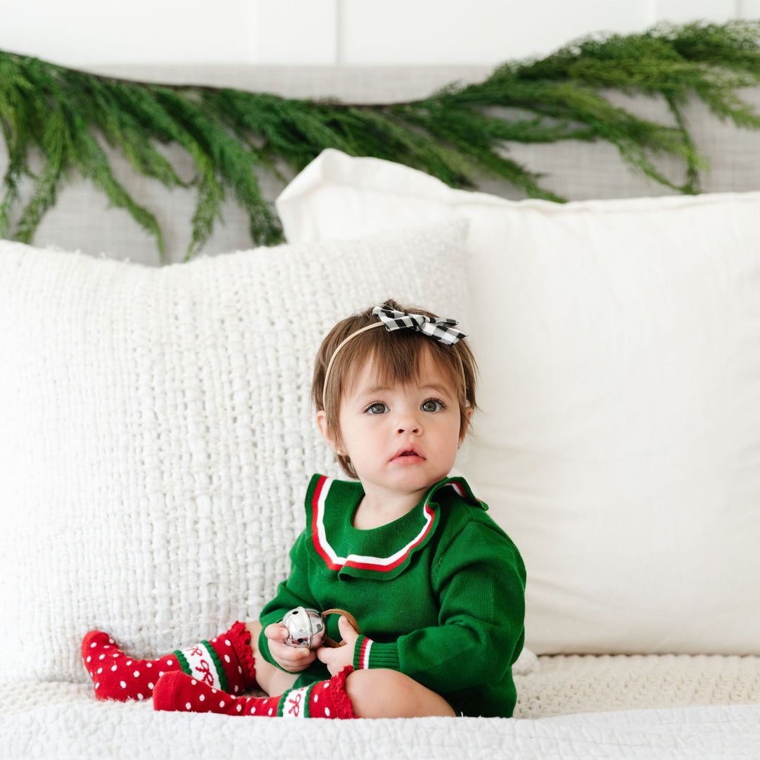 baby girl wearing green christmas sweater romper with red bow knee high socks