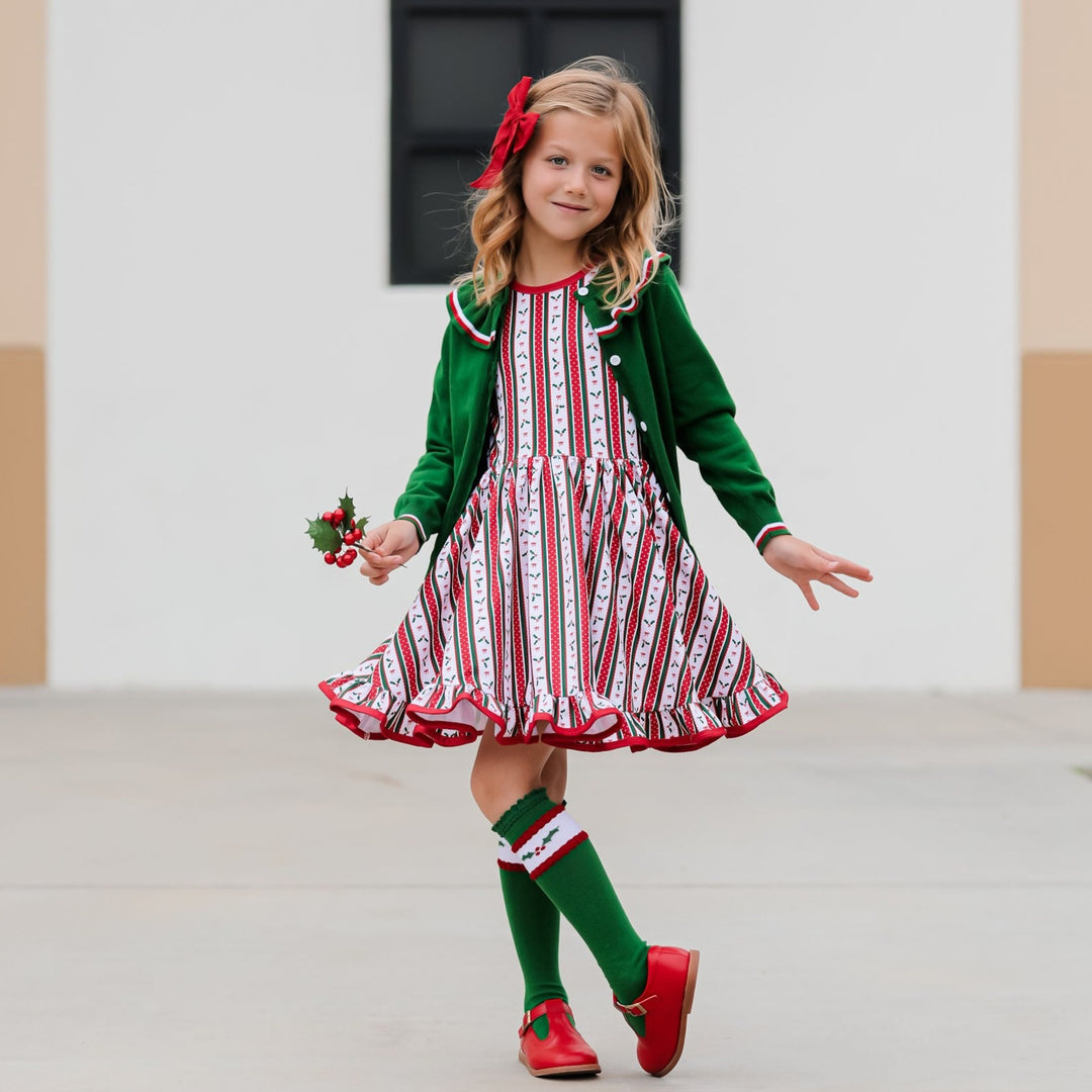 little girl wearing christmas holly wallpaper vintage inspired twirl dress with matching cardigan and knee high socks