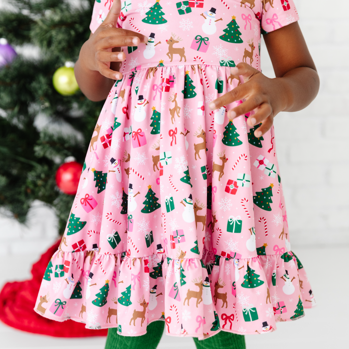 girl wearing pink christmas twirl dress with trees, presents, reindeer and snowmen