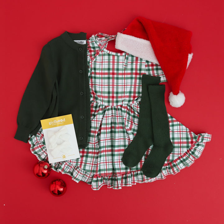 girls christmas outfit flatlay with plaid dress and cardigan and matching knee highs and bows