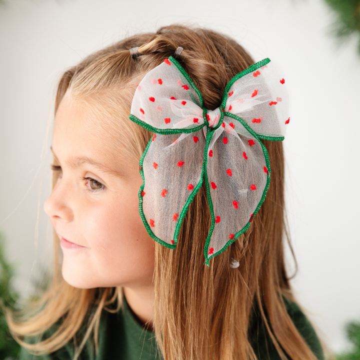 girl wearing sheer christmas hair bow with red embroidered dots and green trim