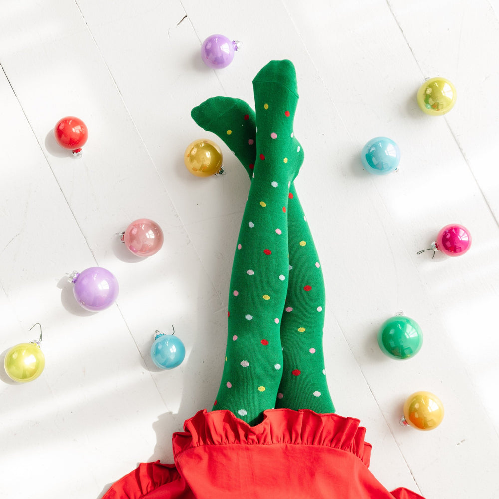 little girl in green Christmas ornament inspired tights with colorful dots paired with red party dress