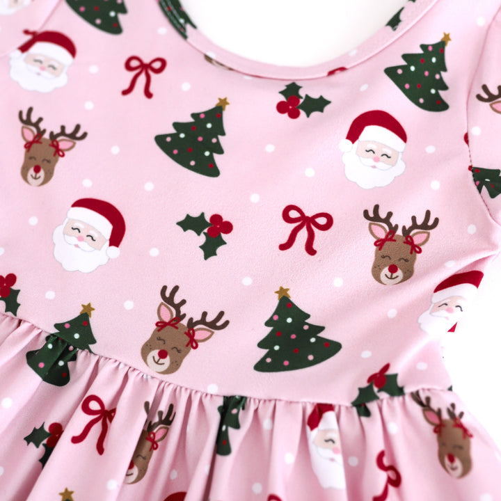 closeup of light pink twirl dress with Santa, reindeer and Christmas tree print