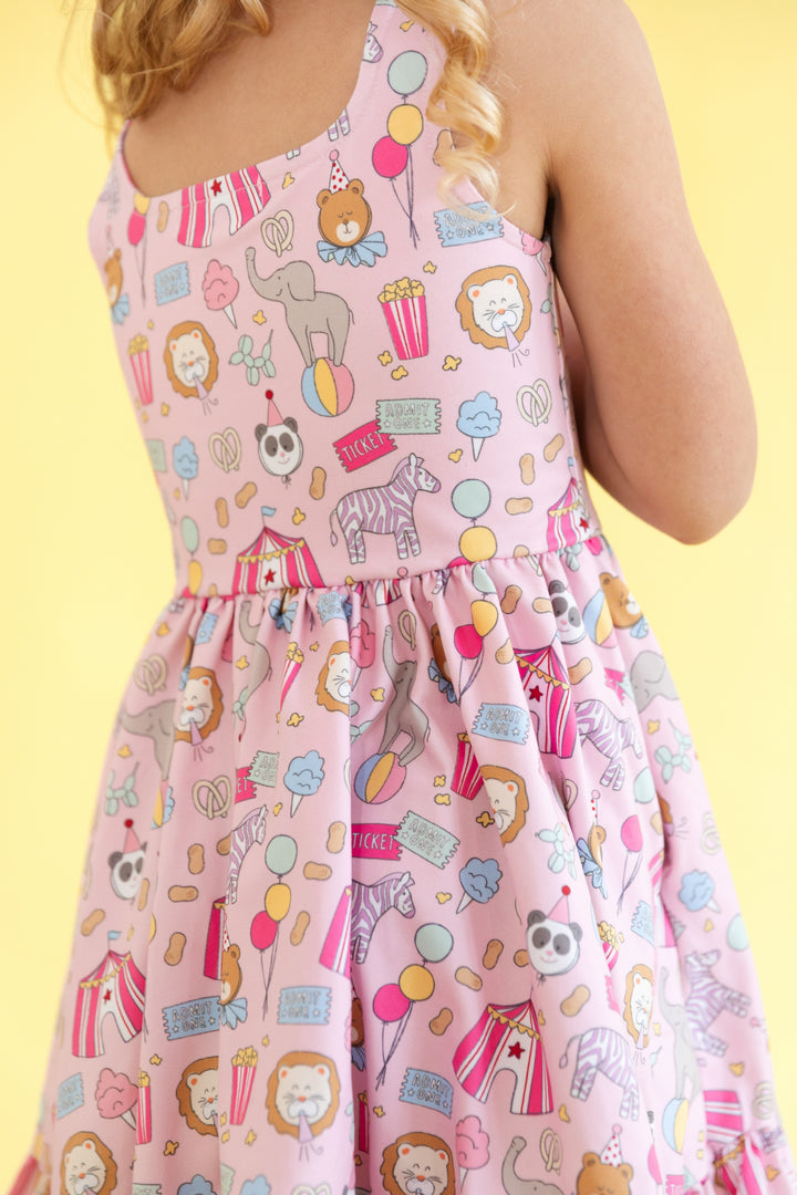 back detail photo of girls' pink sleeveless twirl dress with carnival themed print featuring square neckline and ruffle hem