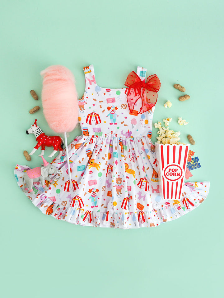 girls sleeveless twirl dress with circus characters, animals, treats and classic rides printed on white and paired with carnival treats