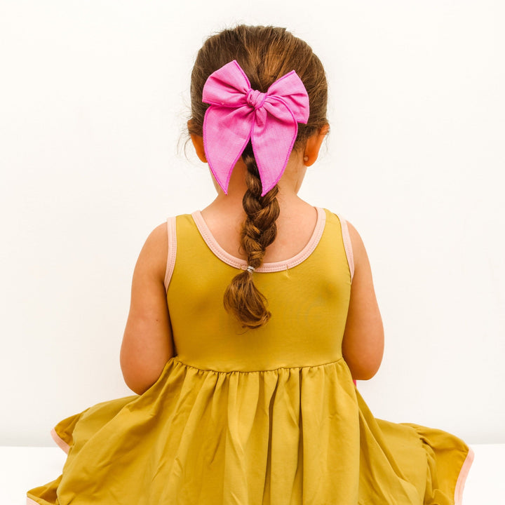 back detail of citron and blush tank dress. Little girl wearing hot pink bow in braided hair