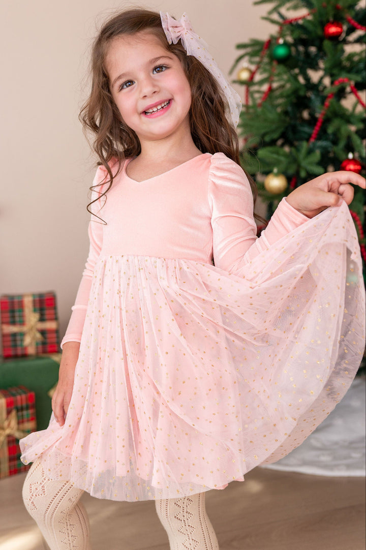 girl wearing pink fancy christmas dress with sparkly gold dotted tulle skirt and matching hair bow