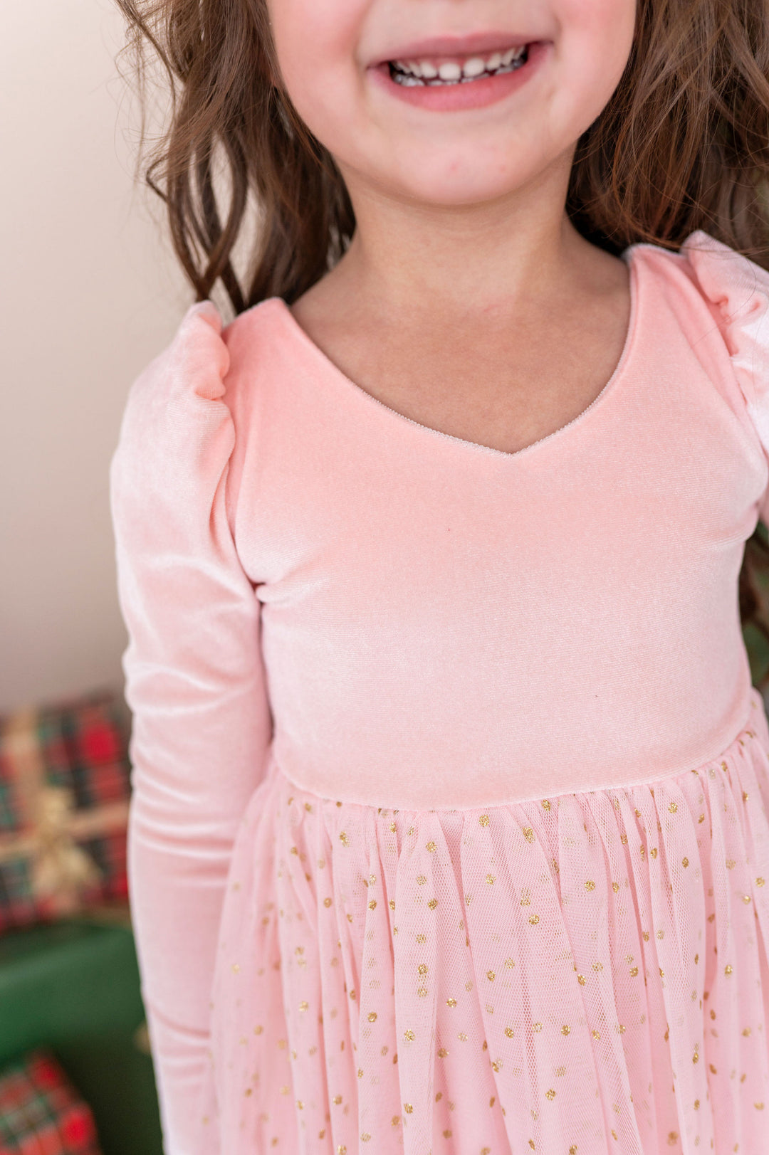 close-up details of girl wearing pink velvet christmas dress with sparkly gold dotted tulle skirt