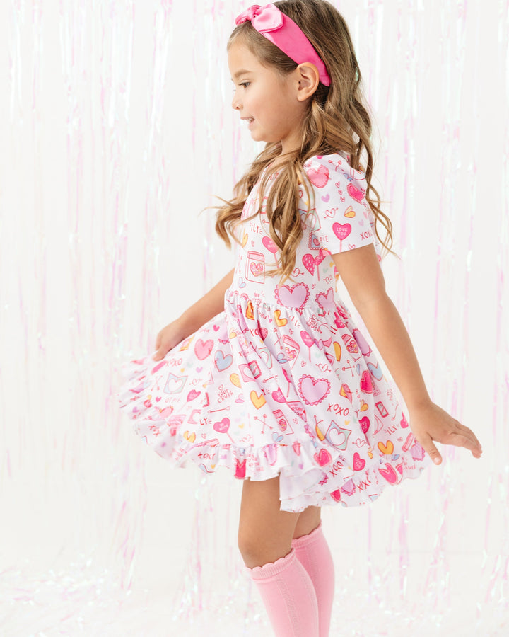 girl twirling in dress with pastel Valentine's Day cards and treats print on white