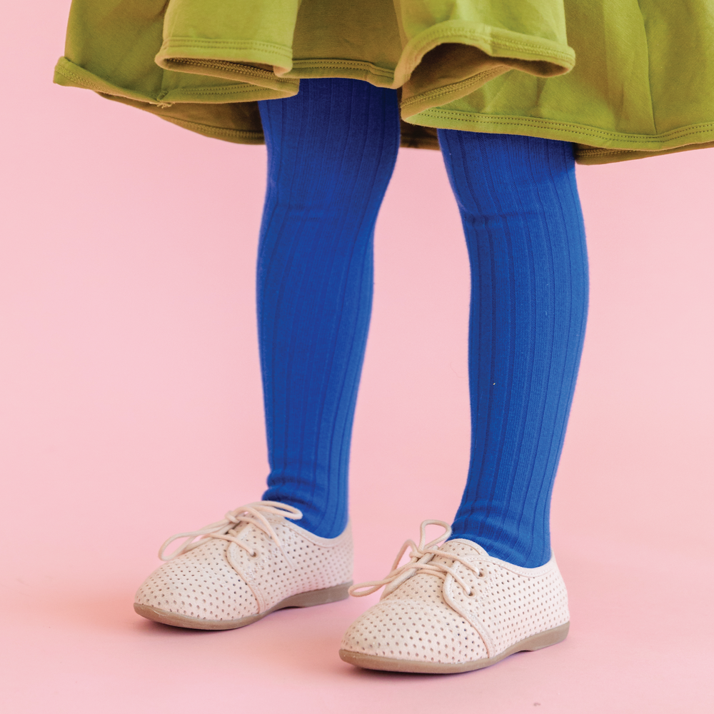 girl in classic royal blue ribbed tights and green dress with pink background