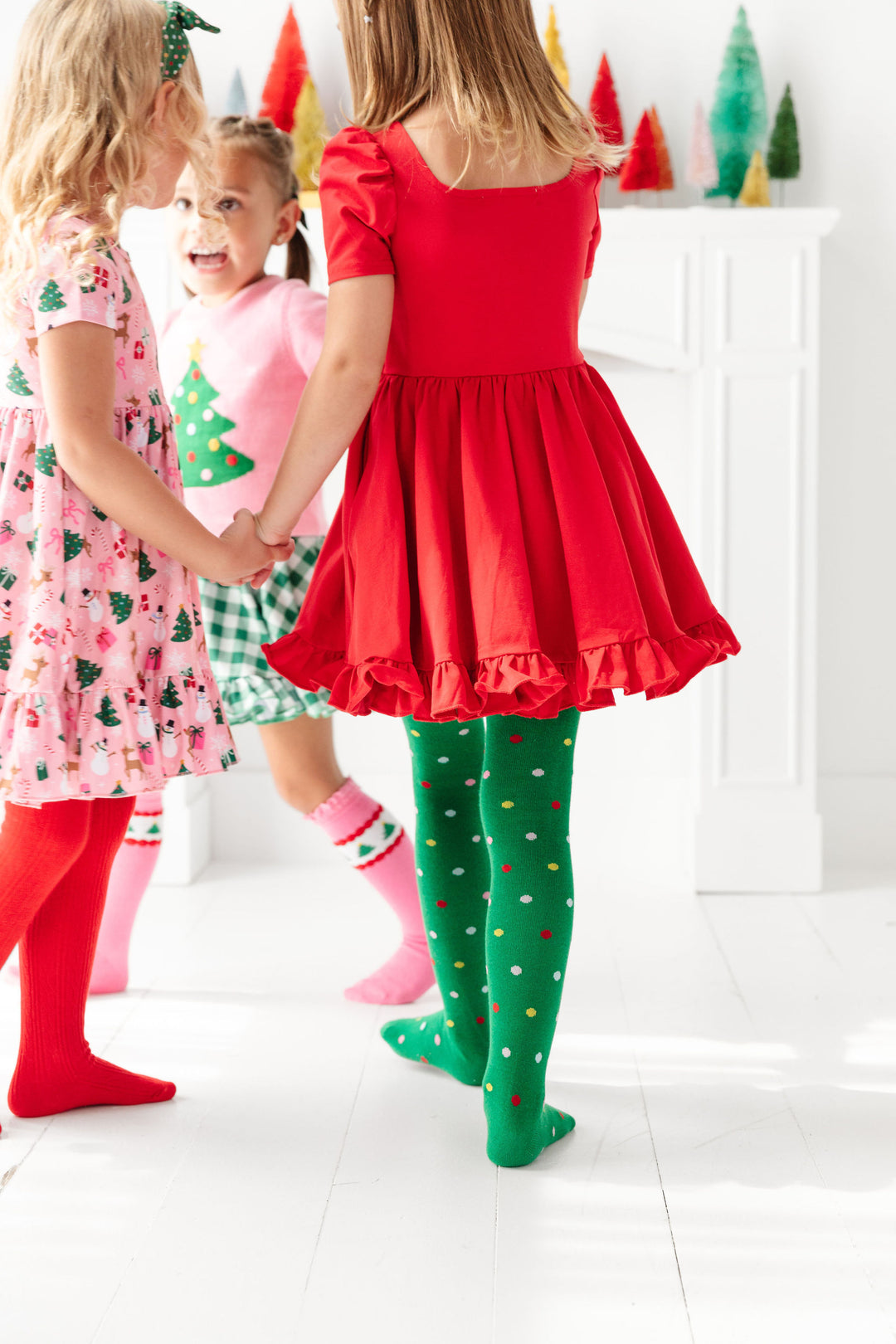 girls playing in red, green and pink Christmas party themed dresses, tights and socks