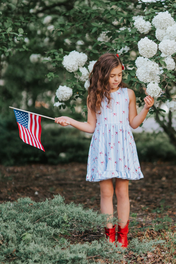 girl in red white and blue stripe dress with bows for fourth of july