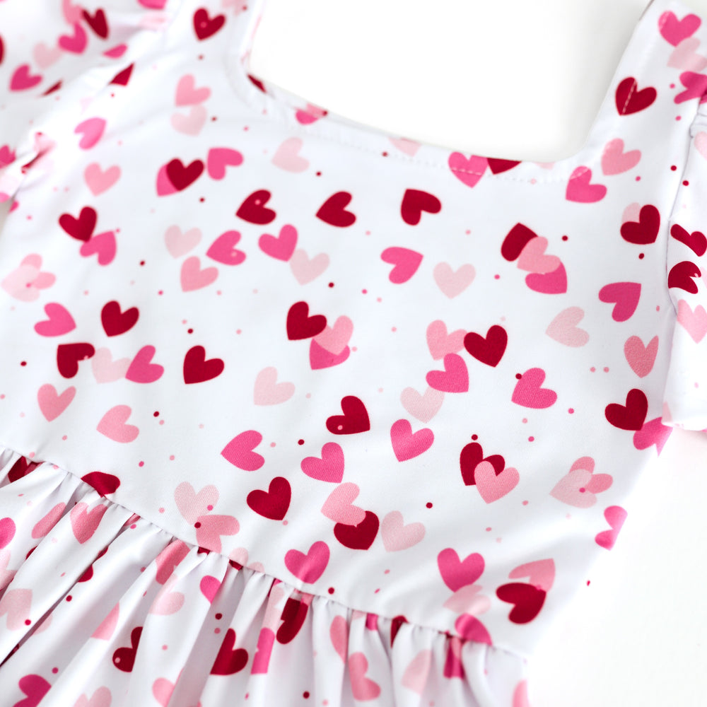 closeup of confetti heart print in shades of pink and red on white base twirl dress bodice