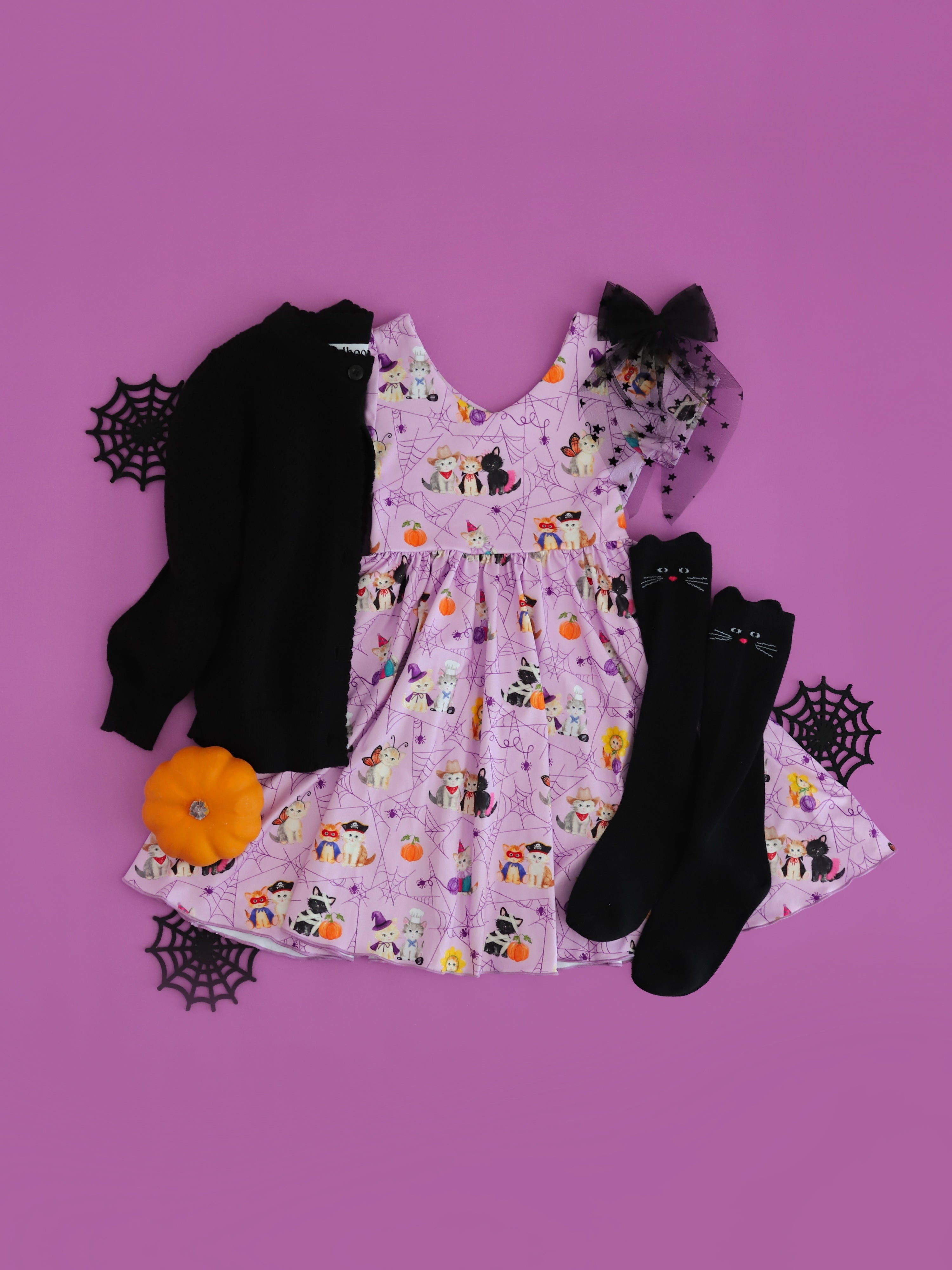 girls' lavender twirl dress with kittens in costume print paired with black open knit cardigan, black cat knee socks and sheer black bow with stars 