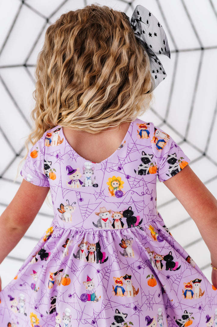 little girl showing v-neck back of lavender Halloween twirl dress with fluffy kittens wearing cute costumes print