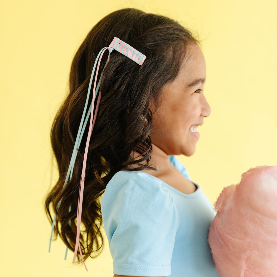 girl wearing light pink and blue cotton candy colored braided hair clip with ribbon tails