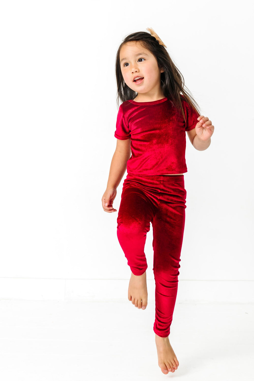 young girl skipping in cranberry red fitted velvet top and matching stretch leggings for Christmas