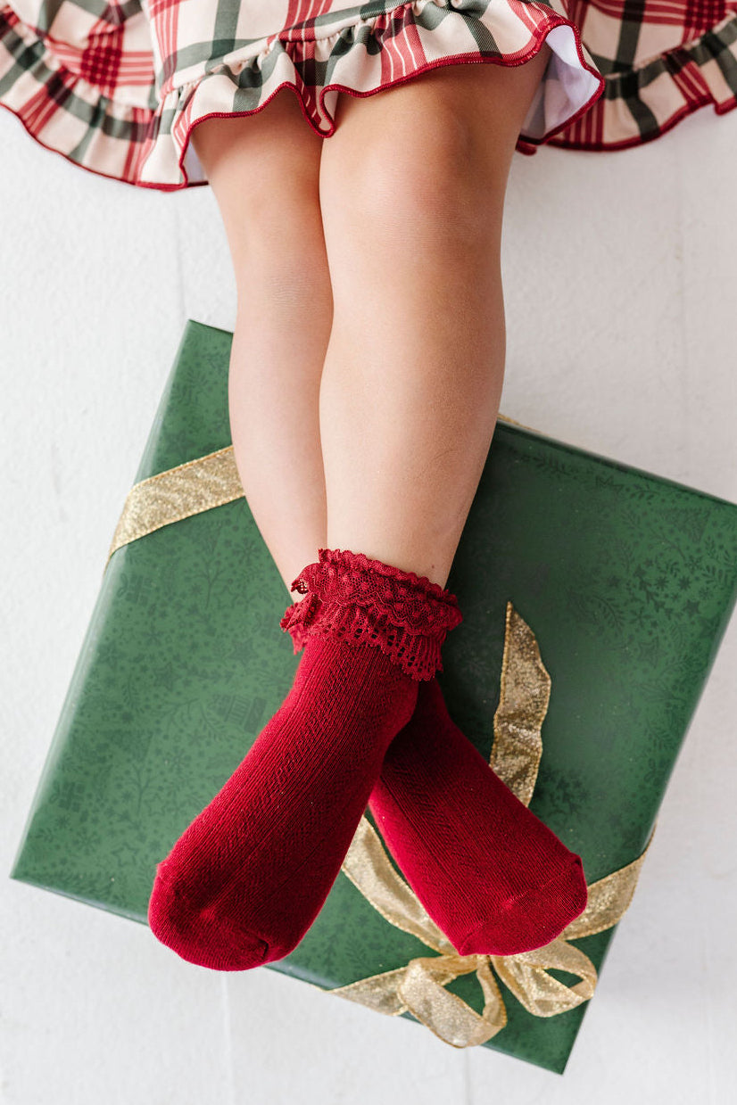 detail shot of girl wearing crimson red fancy lace bobby socks with christmas plaid dress