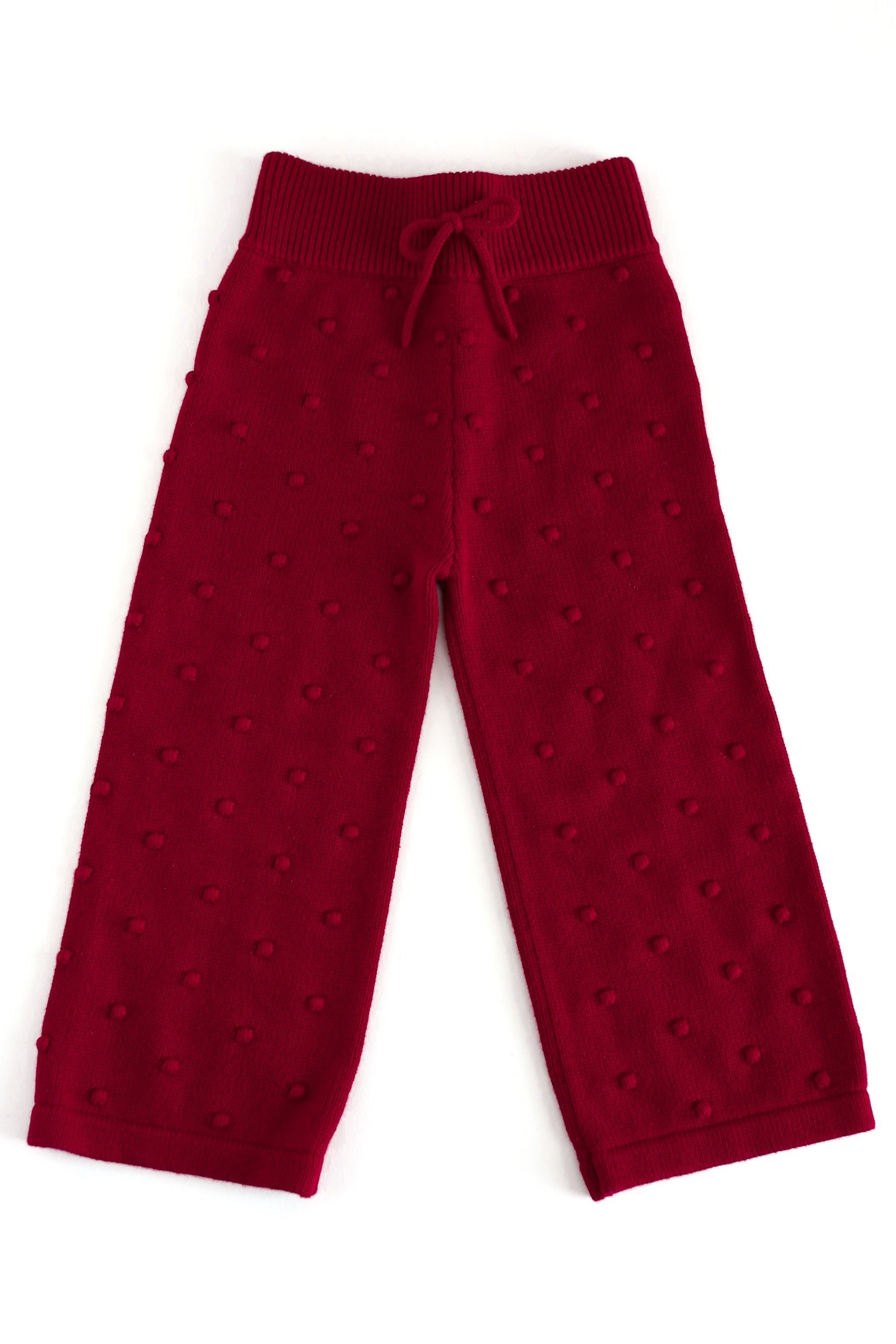A pair of dark red knit pants featuring a textured, raised dot pattern and an elastic waistband with a drawstring, shown flat on a white background.