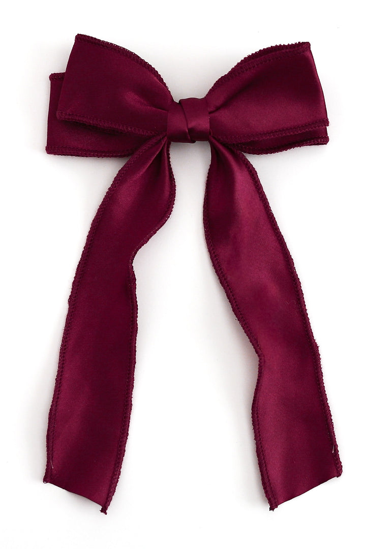 crimson red satin hair bow with long tails photographed on solid white background