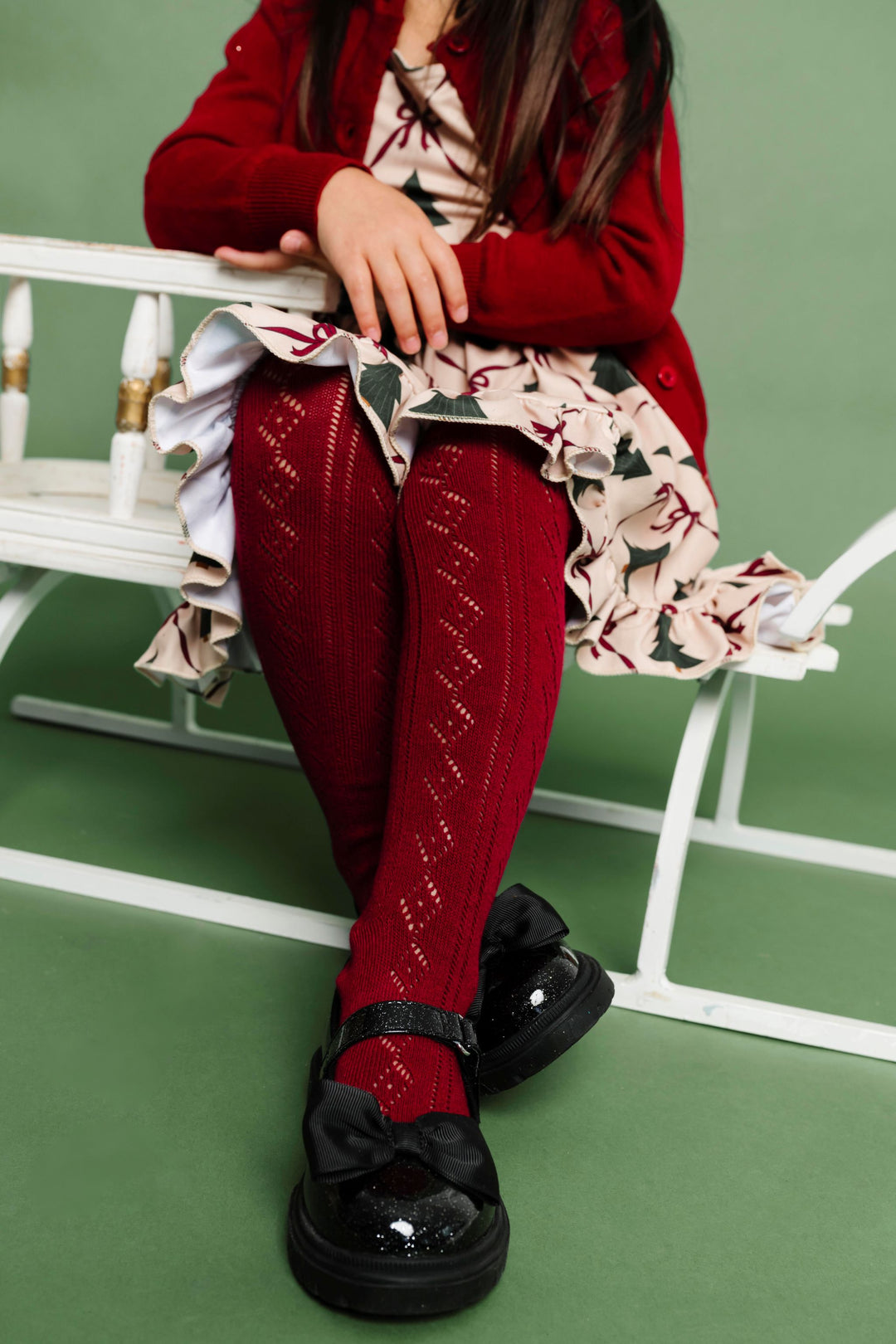 girl sitting on sled in crimson crochet tights to match vintage Christmas tree outfit