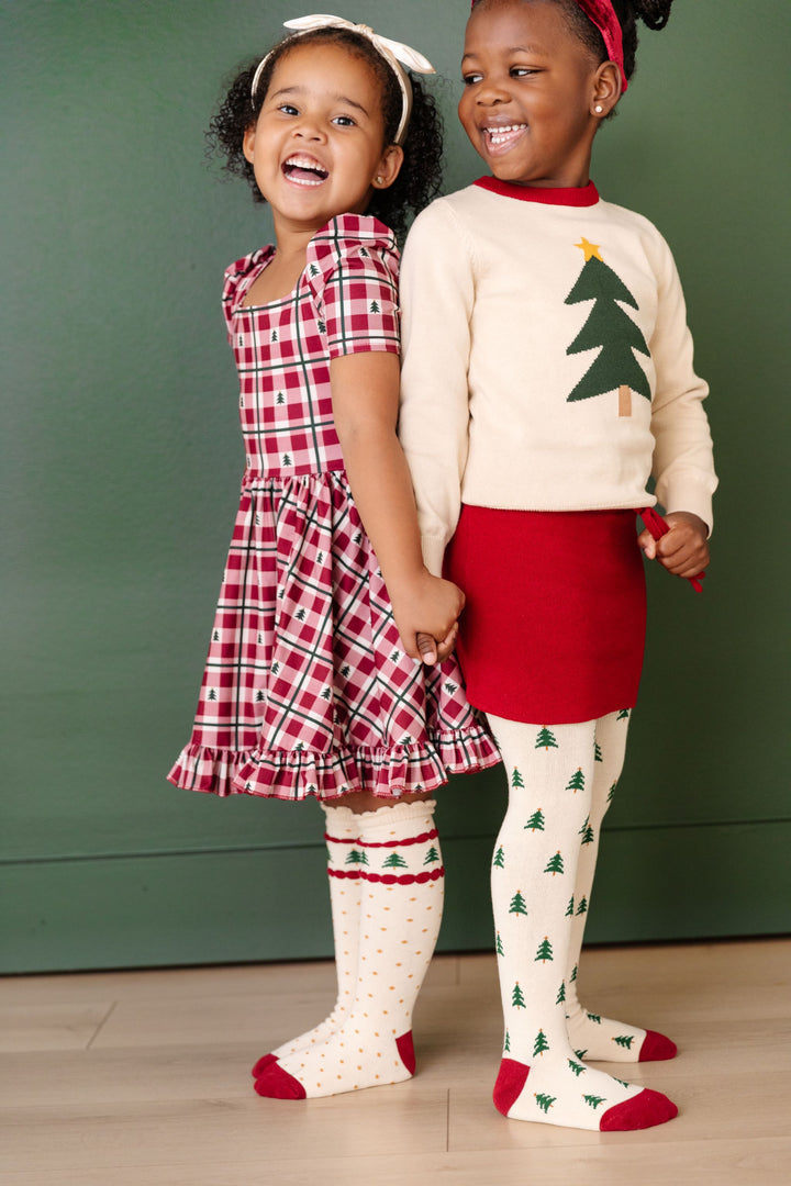 little girls in coordinating Christmas outfits with tree farm theme in crimson red, cream and forest green tree details