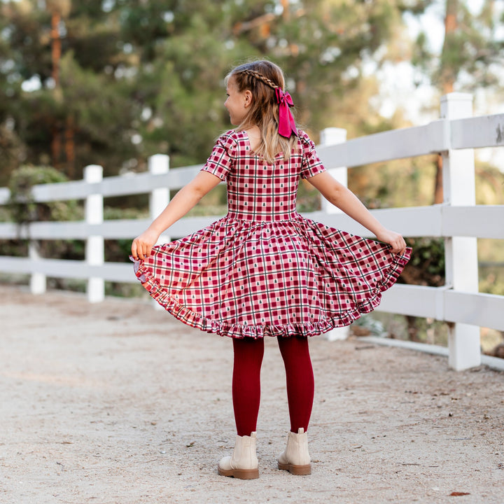 back view of little girls Christmas dress in red gingham with tiny Christmas trees and matching red satin hairbow and tights