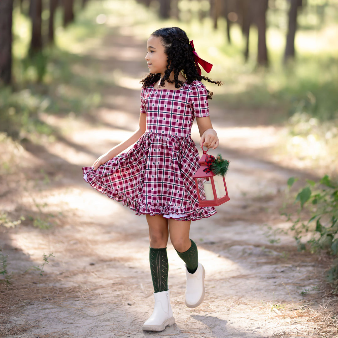 little girl in red gingham holiday dress with Christmas tree details and matching green pointelle knee high socks