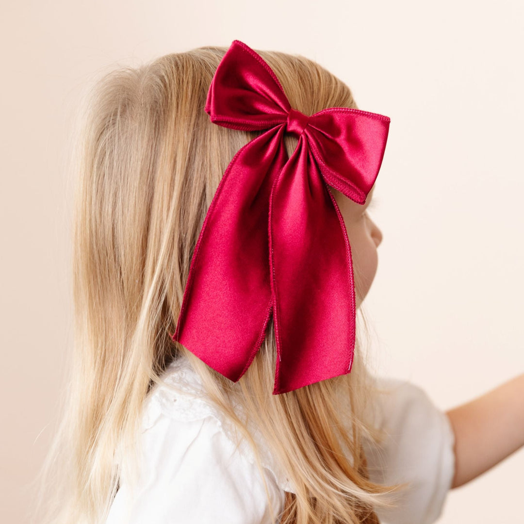 young girl in Christmas crimson oversized satin bow on clip