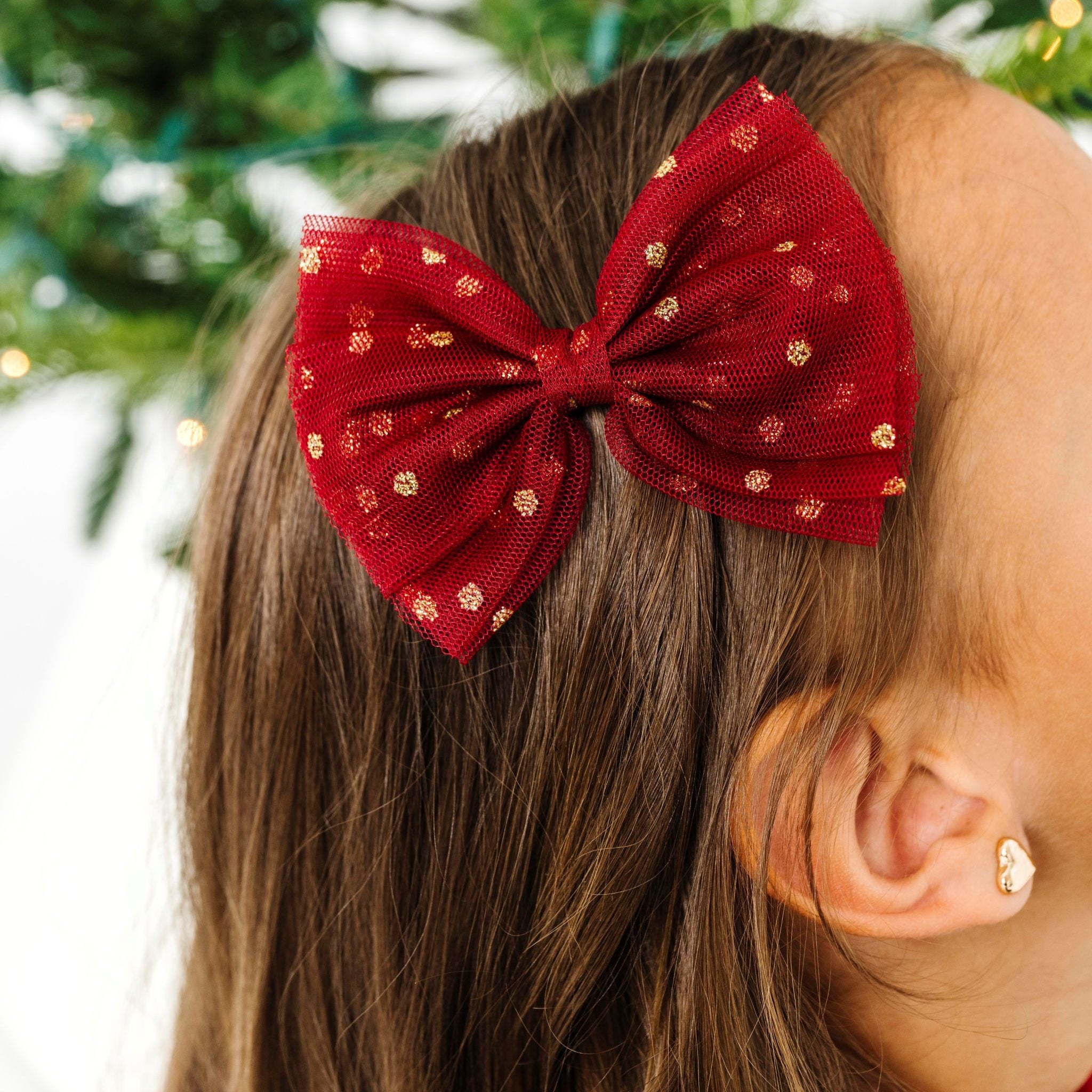 close up of girl in crimson tulle bow on clip with gold sparkles for Christmas