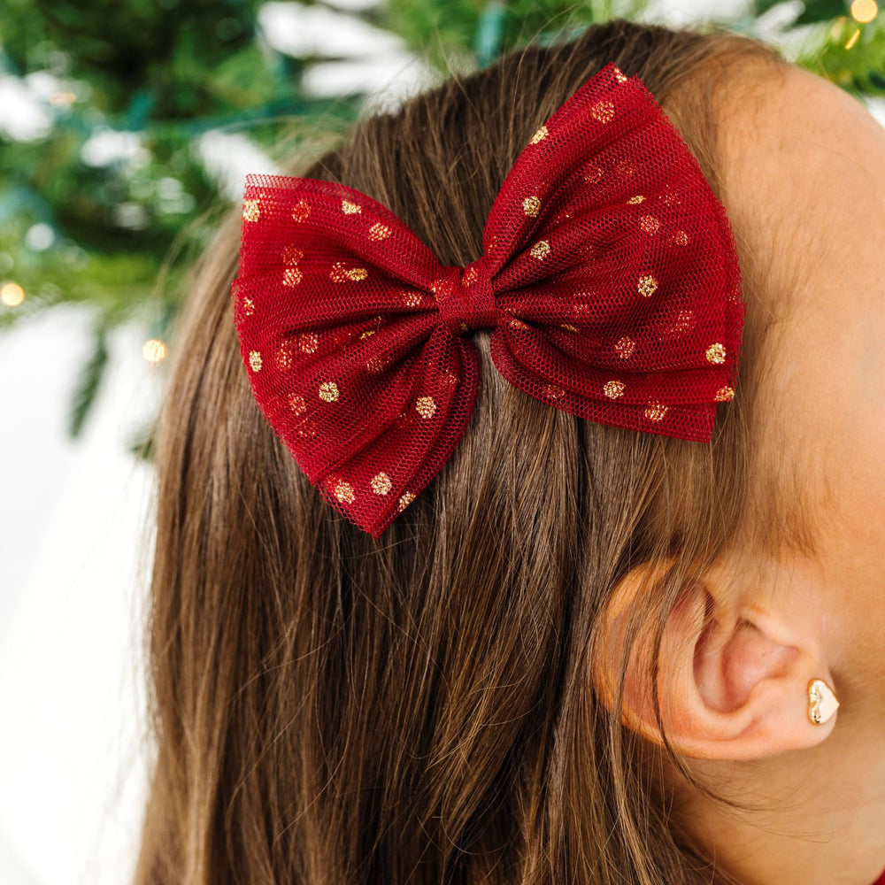 close up of girl in crimson tulle bow on clip with gold sparkles for Christmas