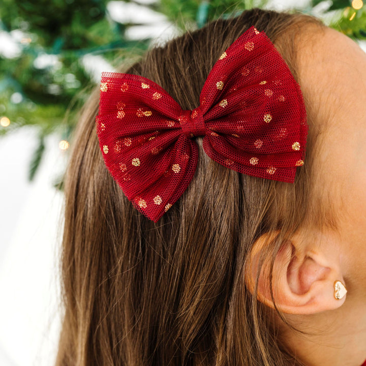 close up of girl in crimson tulle bow on clip with gold sparkles for Christmas