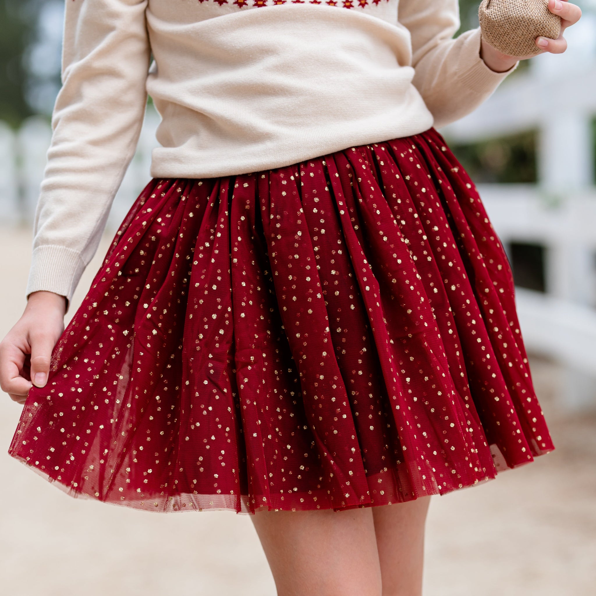 close up of little girl in crimson red tulle skirt with sparkly gold dots for Christmas