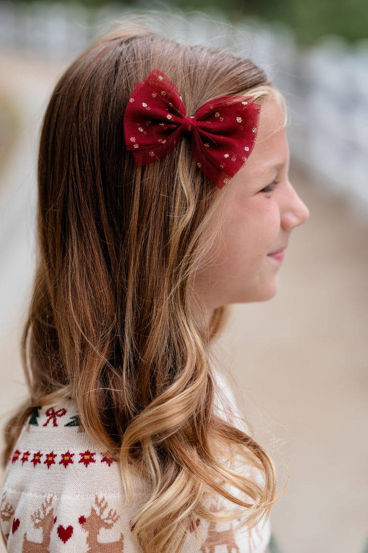 little girl in Christmas fair isle sweater paired with matching crimson tulle bow with gold sparkles