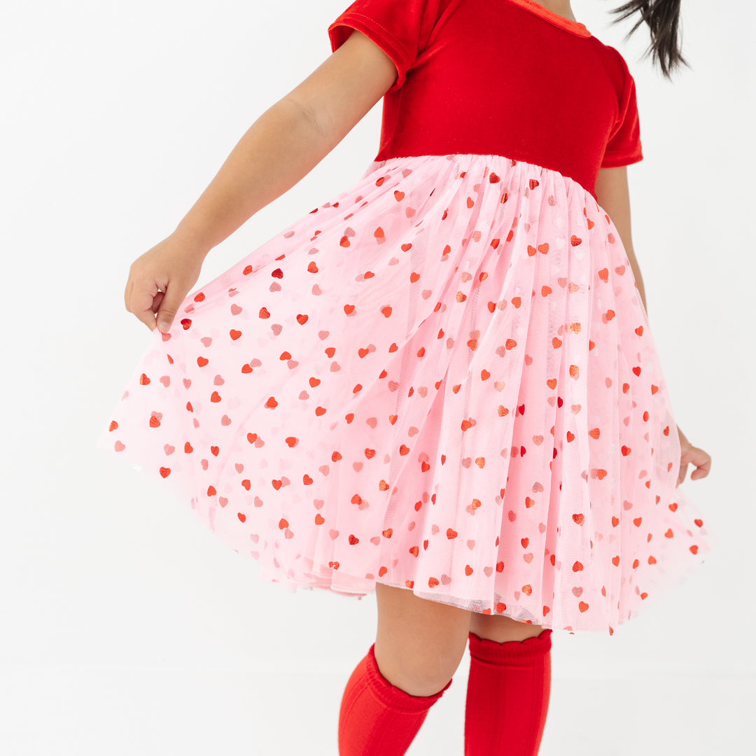 girl holding pink tulle skirt with red hearts and red velvet bodice