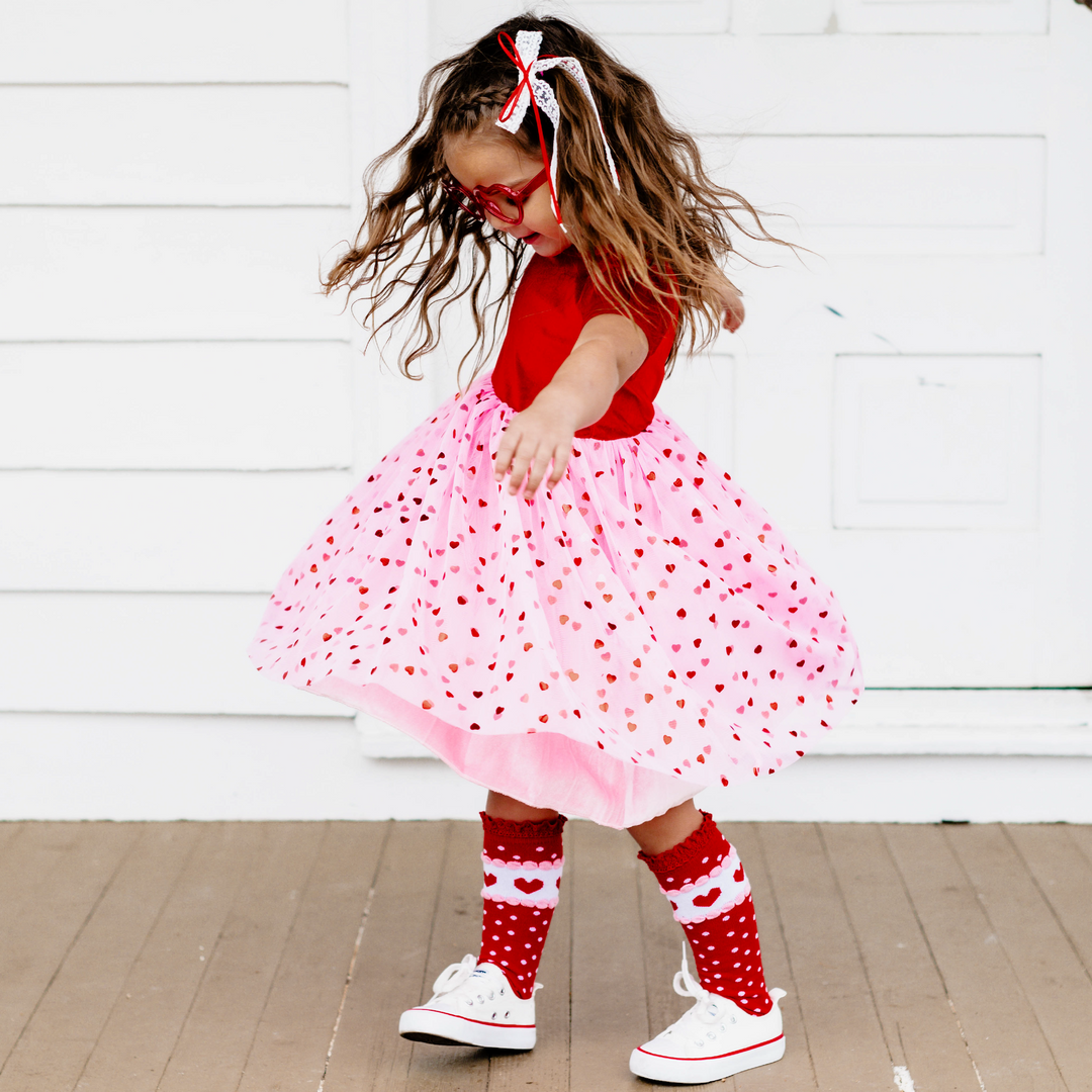 girl twirling in Valentine's Day occasion dress with red velvet bodice and pink tulle skirt with red hearts