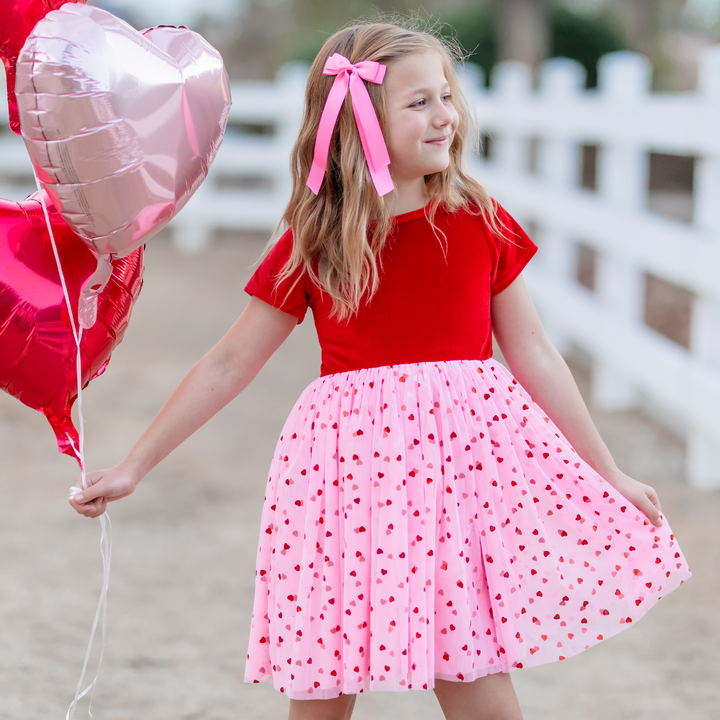 girl wearing red velvet dress with pink tulle heart skirt and pink satin ribbon bow