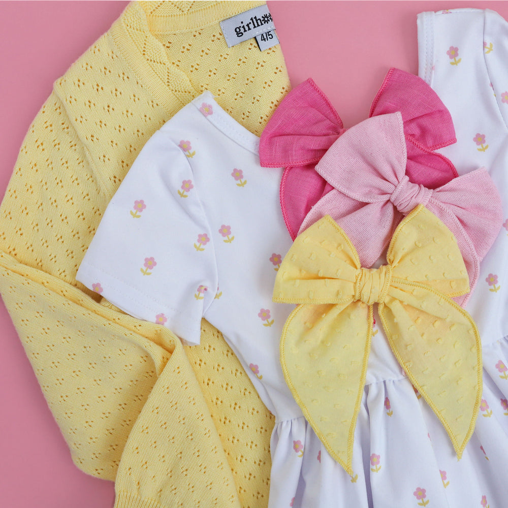 detail shot of dainty floral twirl dress with pastel yellow cardigan and matching spring hair bows