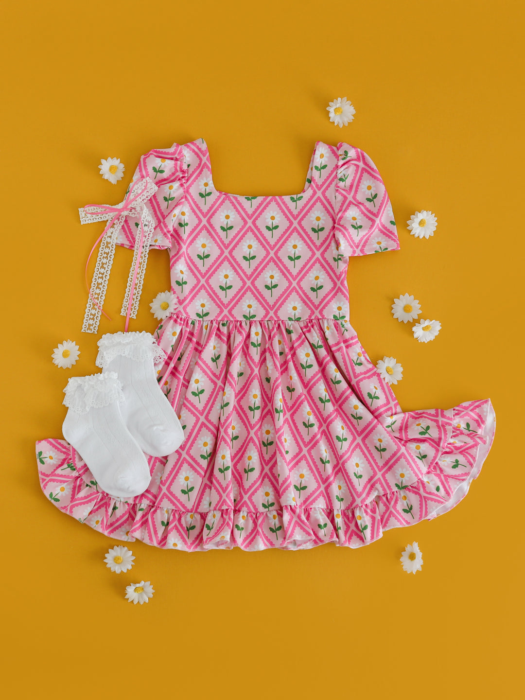 styled photo of girls' pink daisy print twirl dress paired with white lace bobby socks and white lace hair bow