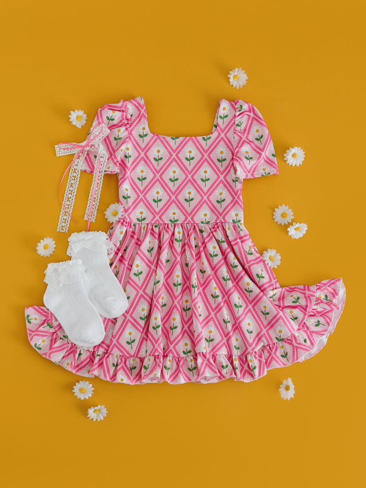 styled photo of girls' pink daisy print twirl dress paired with white lace bobby socks and white lace hair bow