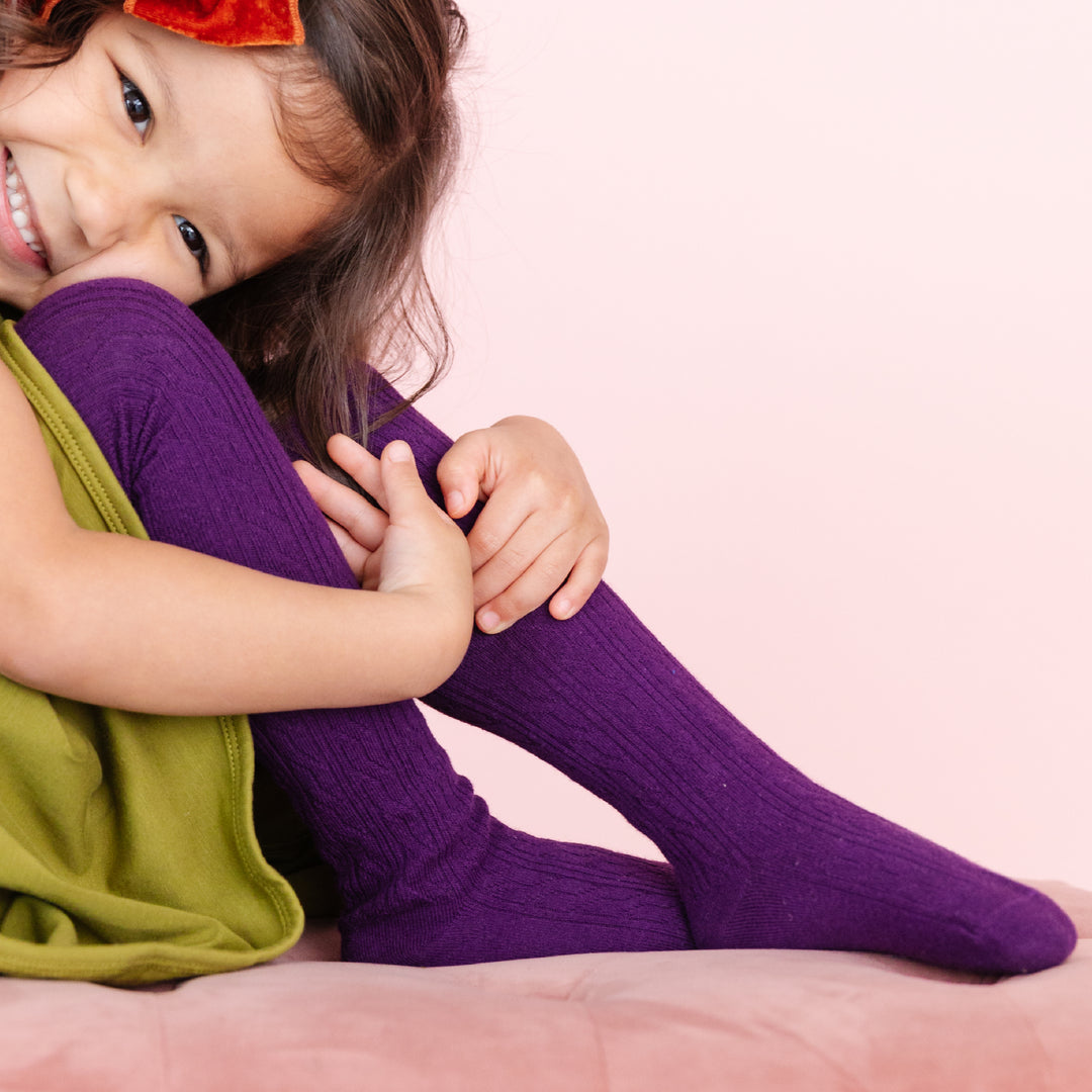 girl in dark purple tights and green dress