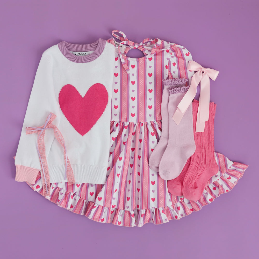 flatlay valentine's day outfit with retro heart wallpaper print and sweater with pink heart and matching knee highs and bows