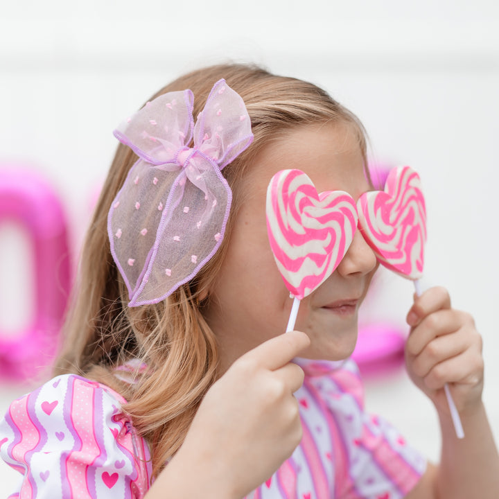 girl in pink sheer dot party girl bow with purple trim and matching valentine's day dress